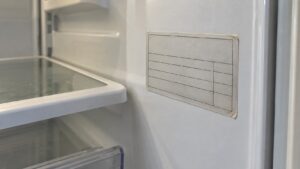 A model and serial number rating tag on the inside wall of a refrigerator compartment, photographed close enough to read
