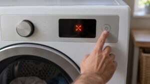 A dryer's control panel display showing an unreadable fault indicator, a hand reaching toward the power button