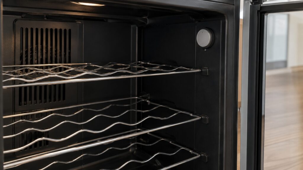 Wire shelving and the interior thermostat dial inside a wine cooler